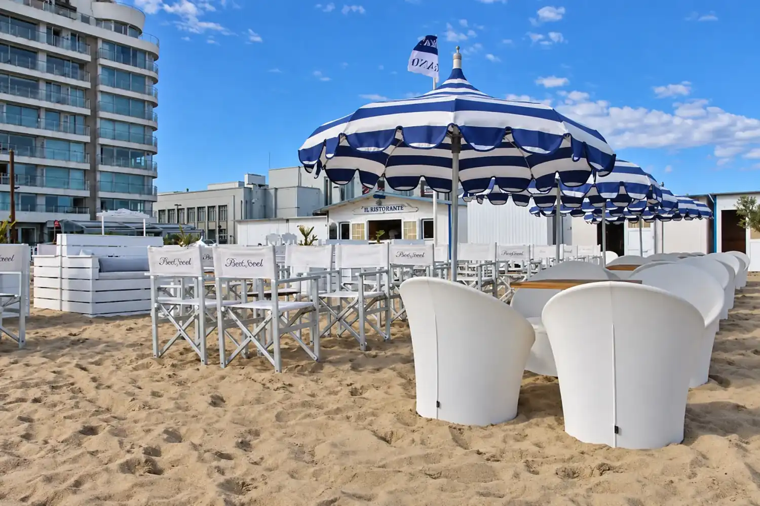 Strandbar met blauw-witte parasols op het zand