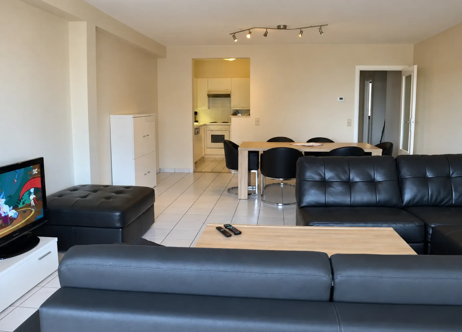 Ruime zithoek met zwarte banken en een eettafel