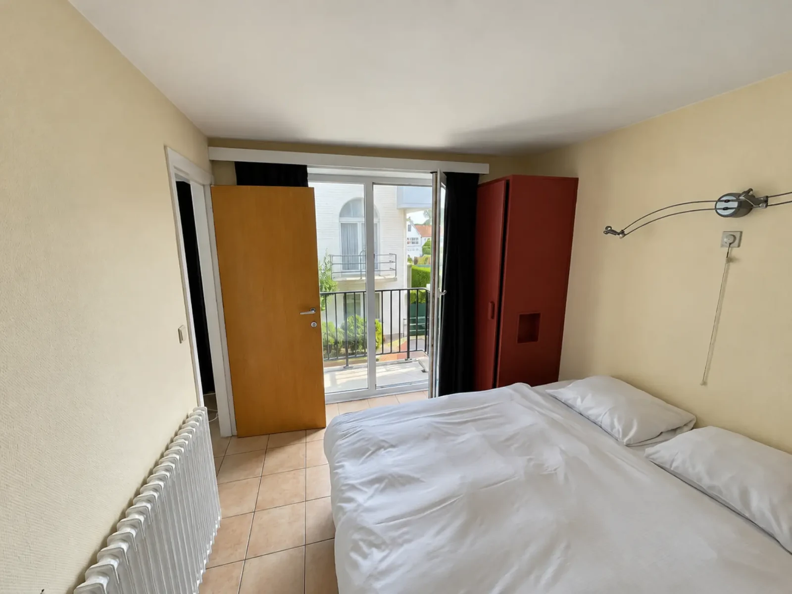 Slaapkamer met wit beddengoed en een deur naar het balkon